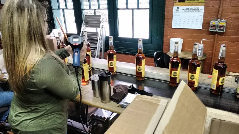 A worker filling bottles by hand on the Buffalo Trace bottling line